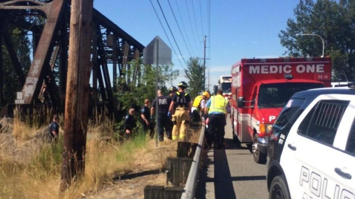 Medics respond to a woman who was hurt after her bicycle was hit by a train in Auburn on Friday afternoon.