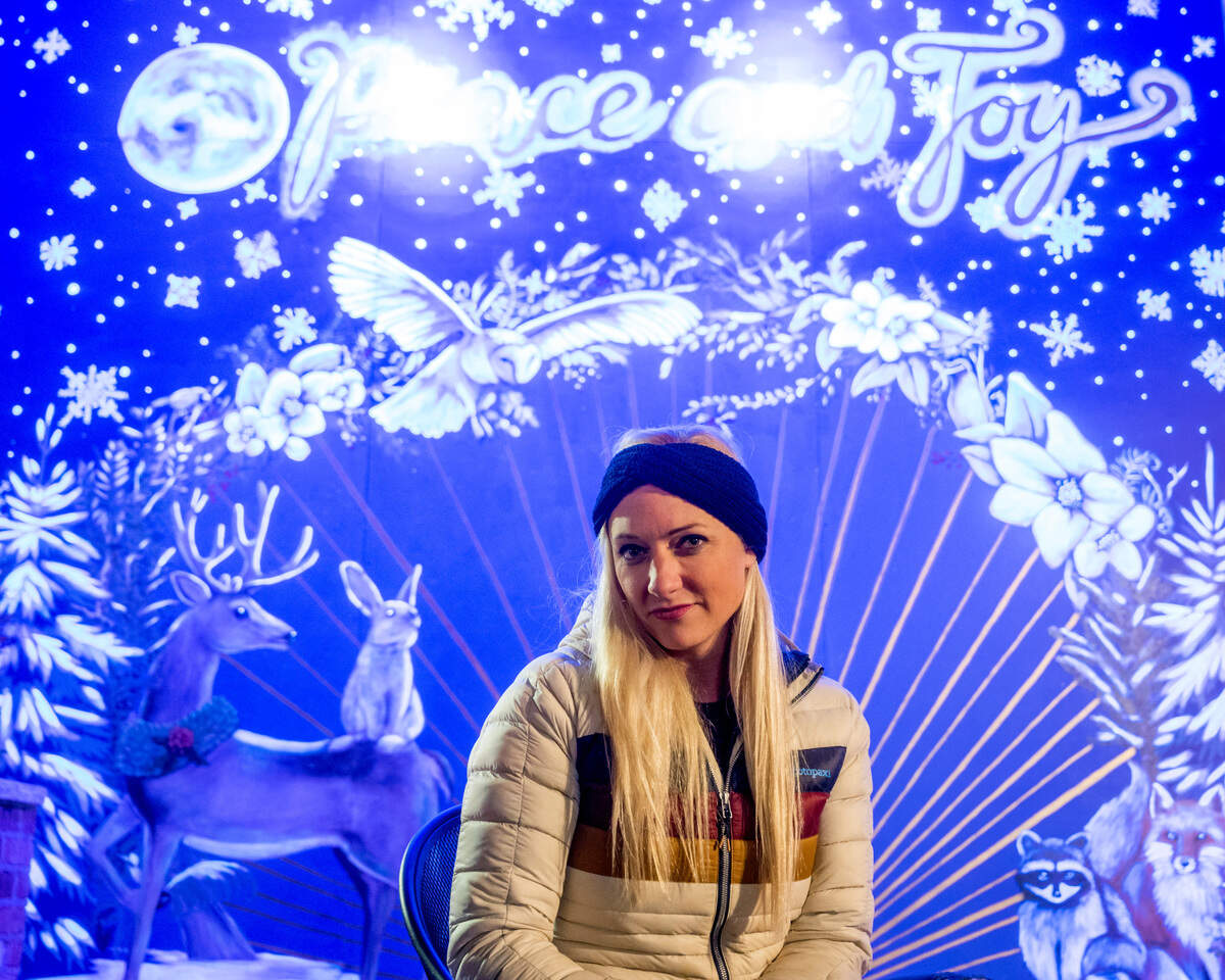 Artist Hillarie Isackson, of Gig Harbor, poses for a portrait in front of the “ultraviolet active” mural along Harborview Drive in Gig Harbor on Sunday evening. Isackson, who plans on creating three more seasonal murals for the city of Gig Harbor, spent two weeks putting this winter mural together.