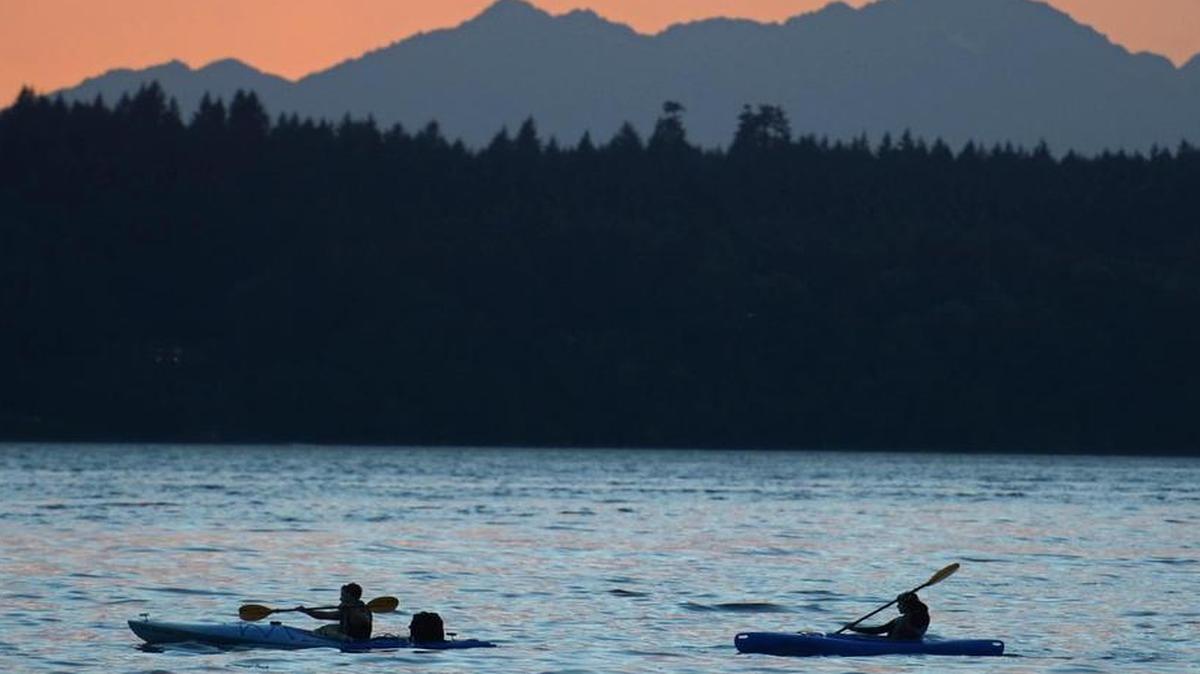 A pair of kayakers paddle down the Puget Sound at sunset near Kopachuck State Park in Gig Harbor on August 3, 2014.