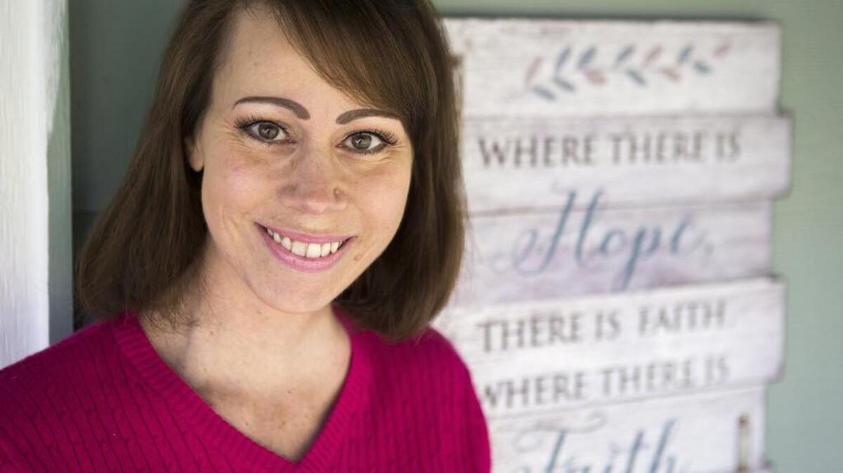 Starla Hauser stands for a portrait next to a sign at her home that she said she’s adopted as a person mantra.