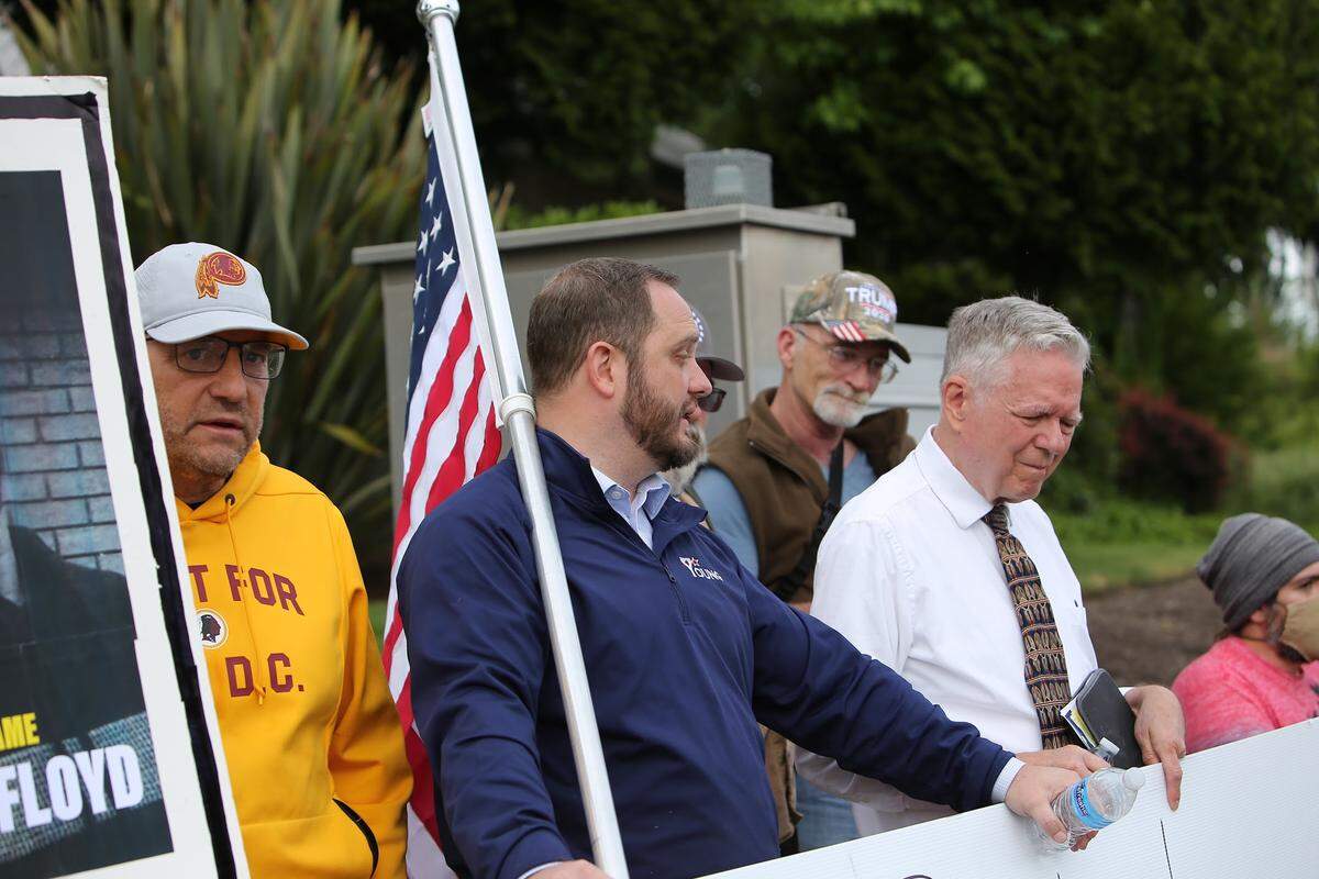 John Skansi (left) former Gig Harbor mayoral candidate and current city council candidate stands next to GOP Rep. Jesse Young (center) at a demonstration in Gig Harbor. Photo by Ronnie Glover.