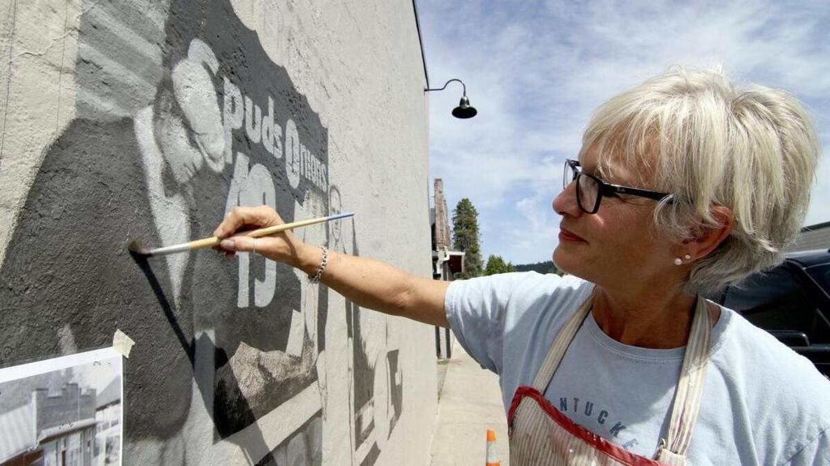 
Lita Dawn Ansich works on the new mural Monday on the front wall at Finholm’s Market in Gig Harbor.

