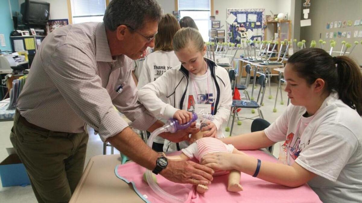 Dr. John Golden guides sixth-graders Kadie Jensen of Key Peninsula Middle School and Kopachuck’s Jackie Morved in how to resuscitate a newborn during a Pediatric Resuscitation workshop at Saturday’s CAPE event.
