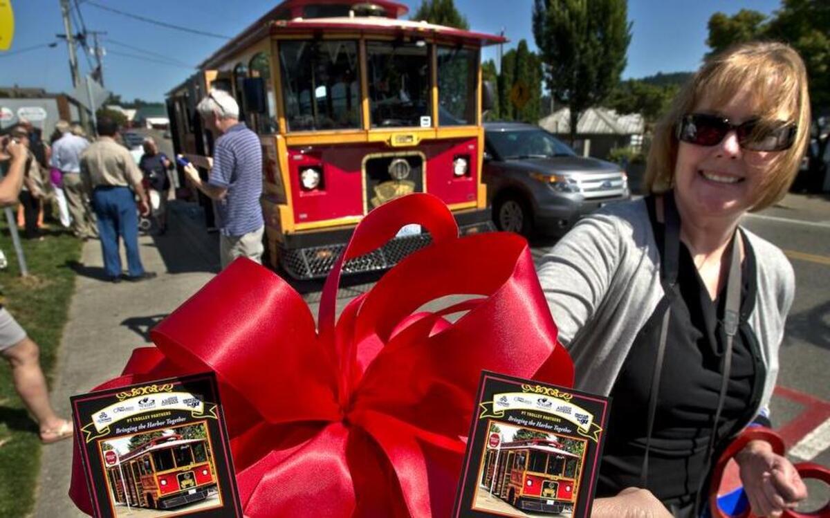 
Gig Harbor Chamber of Commerce’s Tracy Patton shows off keepsakes from Pierce Transit’s Get Around Gig Harbor Trolley service ceremony near Skansie Brothers Park in 2013. 
