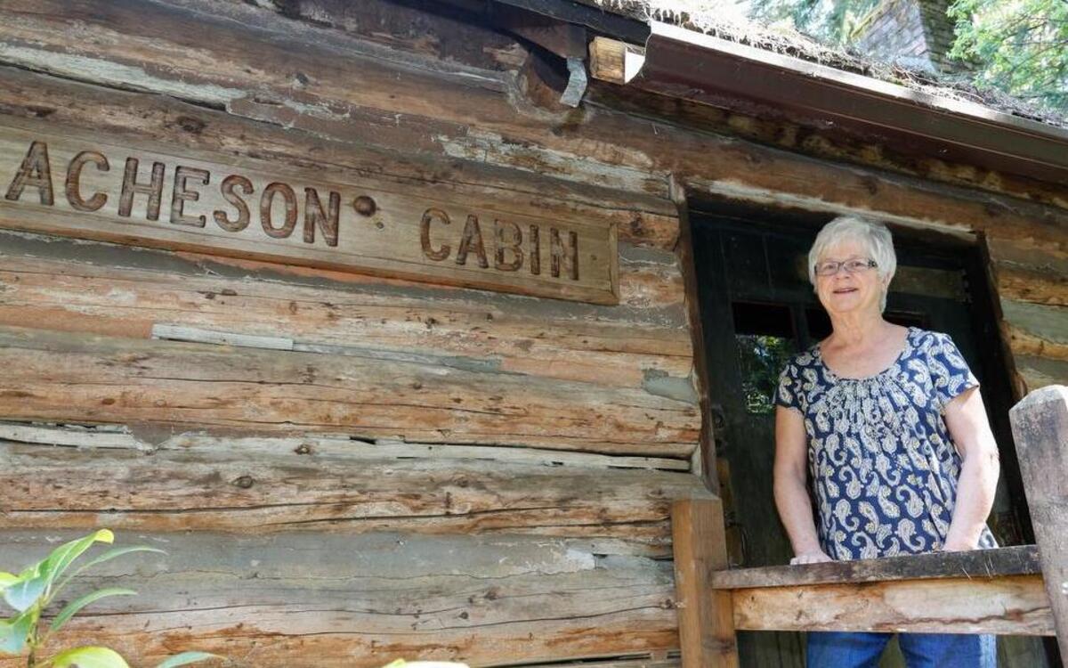 Fox Island Historical Society board member Karen Kretschmer stands in front of the Acheson Cabin at the Fox Island Museum.