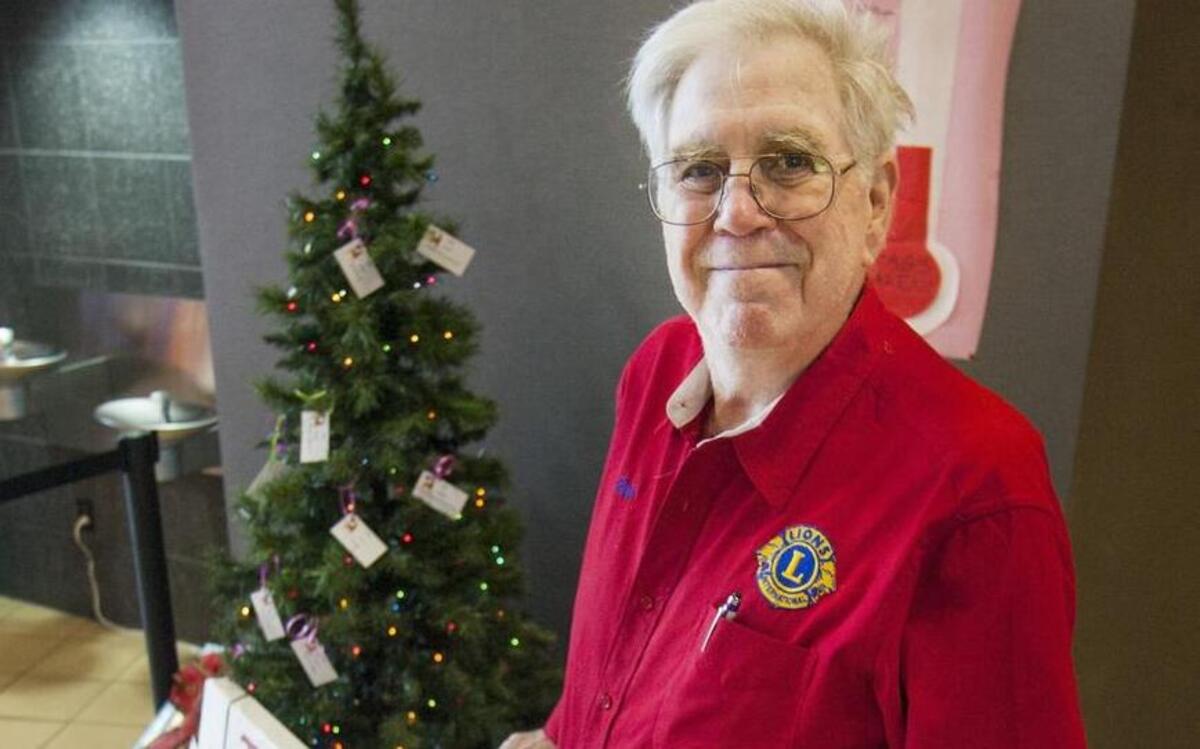 Bob Moore, with the Gig Harbor Lions Club, stands next to a Giving Tree at the Galaxy Uptown Theatre in Gig Harbor. “We look at this as a win-win project to the merchants in our area and the children,” Moore said.