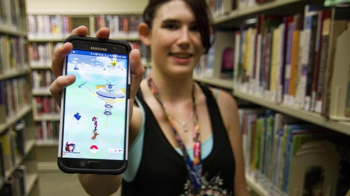 Kaitlyn Griffith, a library page at the Gig Harbor library, shows the library within the Pokémon Go game on her phone. The library is embracing its role as a gym in the popular mobile game. Several pages. including Griffith, try and take over the gym within the game during their breaks. Griffith says she has seen about 20 kids a day playing the game during her shifts.