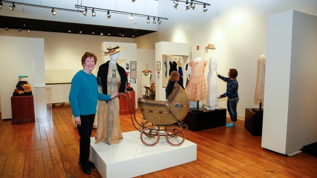 Harbor History Museum curator Joann Hale, left, begins setup for the new exhibit, “50 Years of Fitting In,” while volunteers Cassondra Baglio, right, and Leann O’Neill adjust another artifacts. The exhibit opens to the public on Saturday (April 16) and runs through July 17.