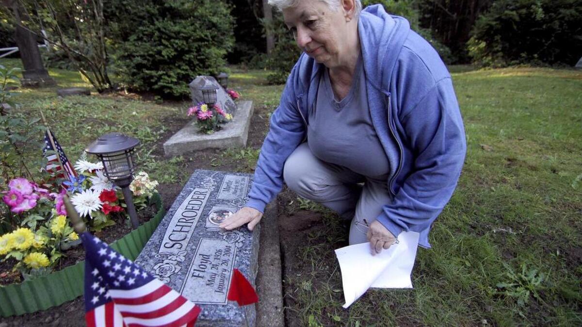 
Daughters of the American Revolution chapter member Kathy Veasey cleans fallen leaves from the grave stone of Floyd and Myrtle Schroeder on Monday morning at the Gig Harbor Cemetery.
