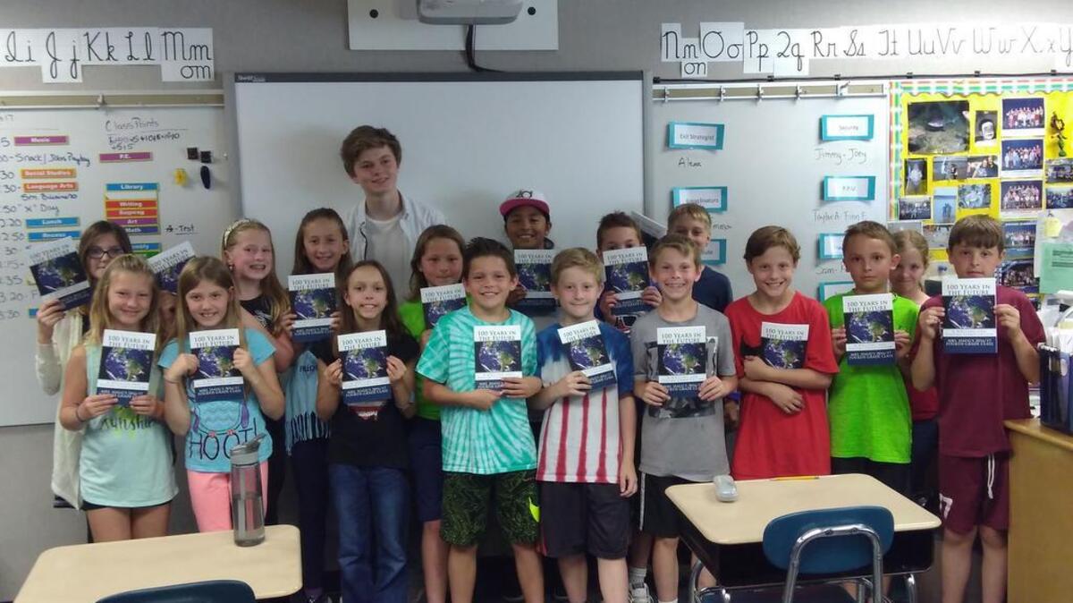 Gig Harbor High student Finlay Adamson is surrounded by fourth-graders in Rhonda Haug’s class at Voyager Elementary who show off their books their writing is featured in.