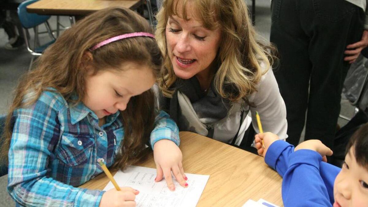 Community member Nonie Whalen chats with Artondale Elementary first-graders Ella Merck and Joshua Parks while visiting the school as part of last week’s bus tour of the Peninsula School District.