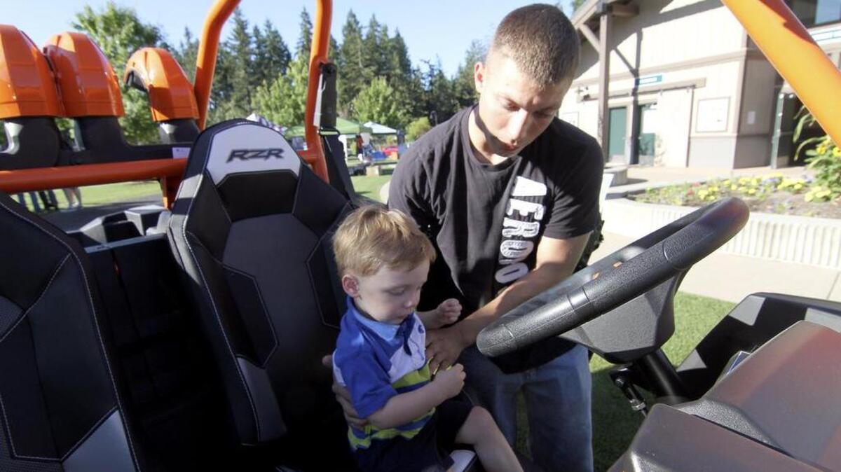 Wes Ardner lets his son Zaddock get behind the wheel of a static displayed Razer UTV brought to Military Appreciation Day in Gig Harbor by the folks at Costco.