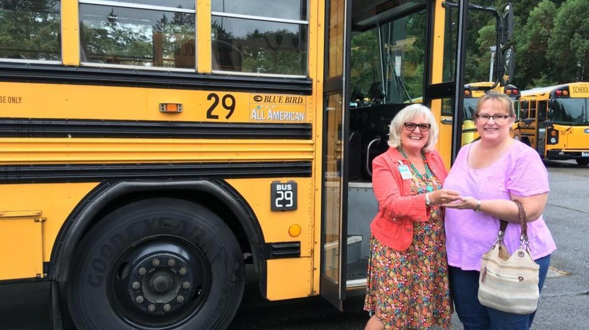 Peninsula School District Director of Transportation Annie Bell, left, passes keys to a loaner school bus to a Puyallup School District representative on Aug. 31.