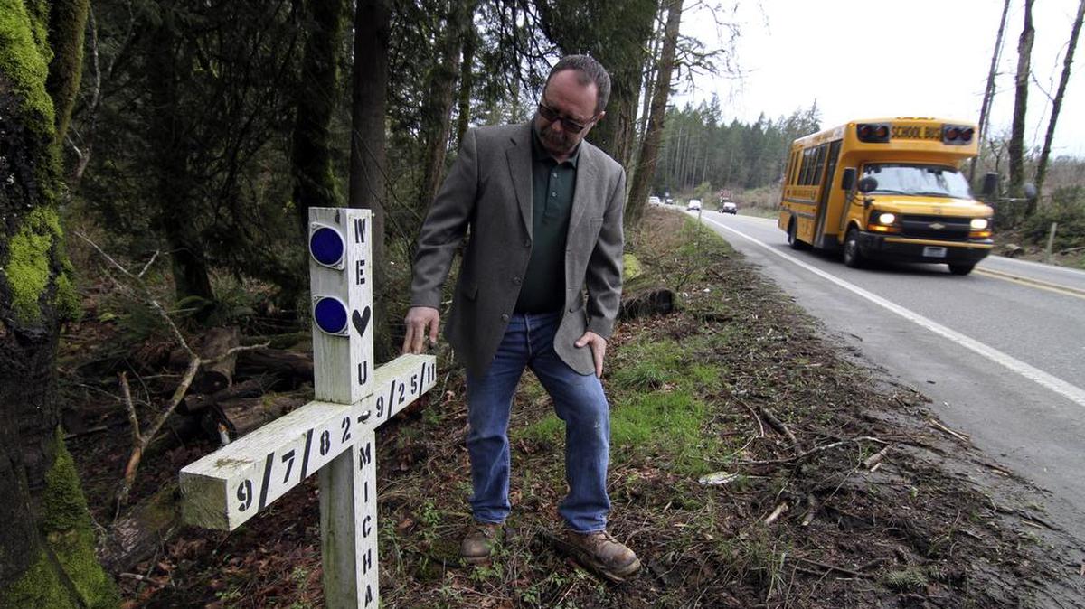 Chuck West, a member of the Key Peninsula Community Council and Safety Committee member, looks over the roadside memorial for Michael Barrett, a young man who died in a single-car collision as he was driving home from a night shift at a restaurant along the Key Peninsula Highway near state Route 302. West and many other supporters are hoping to make many improvements to the notoriously dangerous roads on the Key Peninsula.