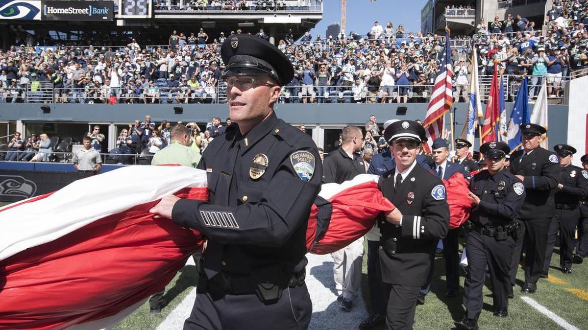 Gig Harbor police Lt. Fred Douglas helps carry the field-sized American flag onto the football field for the national anthem and 9/11 moment of silence before Sunday’s NFL season opener at CenturyLink Field in Seattle. Other Gig Harbor officers who participated included Sgt. Darius Aldridge, officer Carson Abell, officer Jarab Daniel and officer Adam Blodgett.