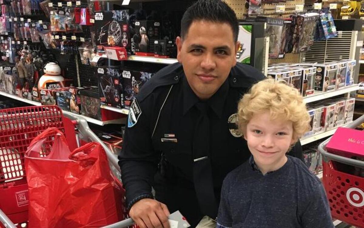 Gig Harbor Police Officer Eddie Dominguez stands with a student from the Peninsula School District during the 12th annual Holiday Heroes event Tuesday at the Gig Harbor Target.