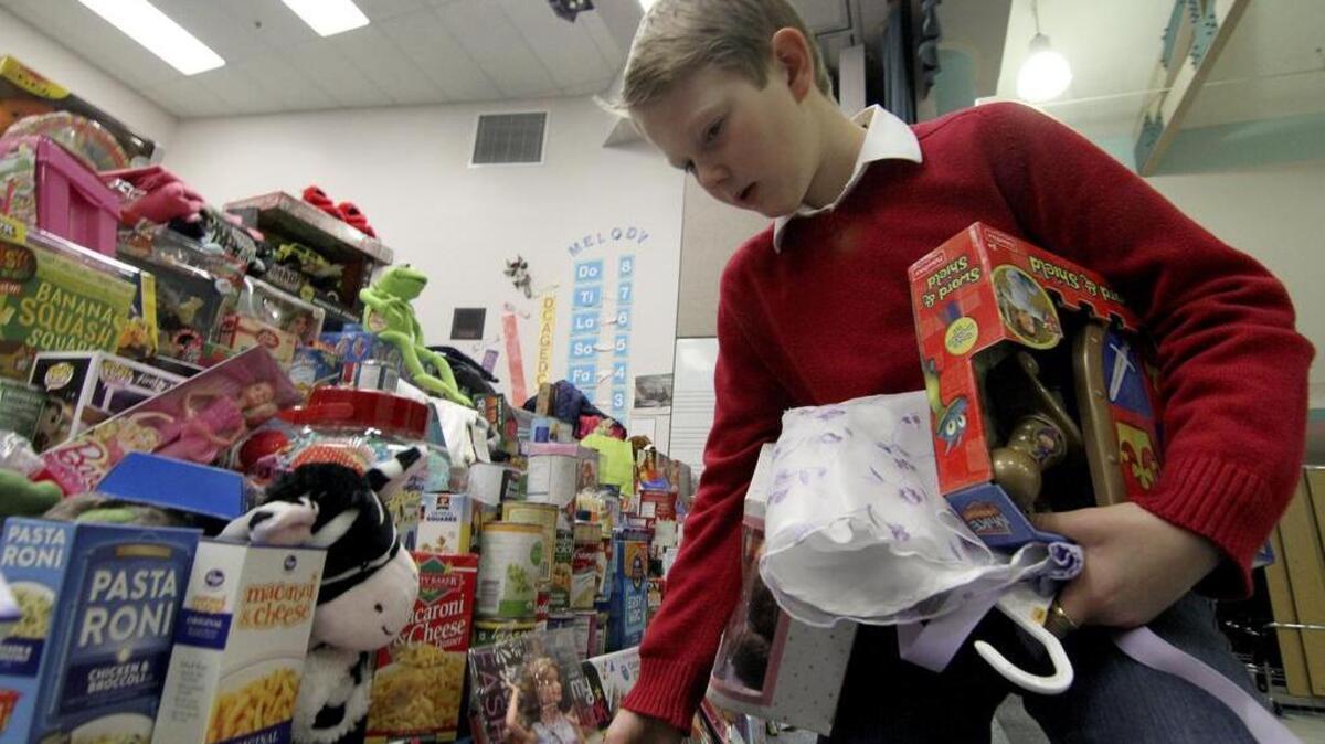 Student Finn Miller, 9, places donated toys on the stage last week at Harbor Heights Elementary School’s 16th annual Sharing and Caring assembly. A mountain of donated non-perishable food, toys and clothes took up the school’s stage.