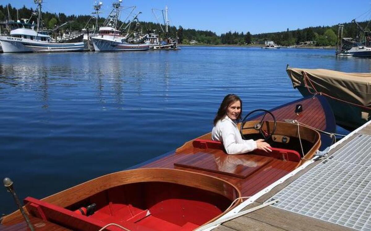 Gig Harbor BoatShop business manager Sheri Lovrovich sits in the Gaylynn, a wood boat that will be part of the Fourth Annual Classic Boat Show, hosted by Tides Tavern on Saturday and Sunday (May 14 and 15).