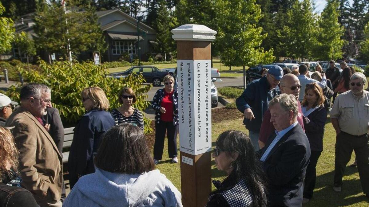 People walk around and view the Peace Pole after an unveiling ceremony Monday in front of the Gig Harbor Civic Center.