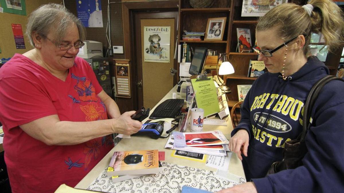 Mostly Books owner Jo Graffe helps customer Rachel Vasquez last week during a closing of business sale. The landmark harbor business has faithfully served its customers for nearly two decades.