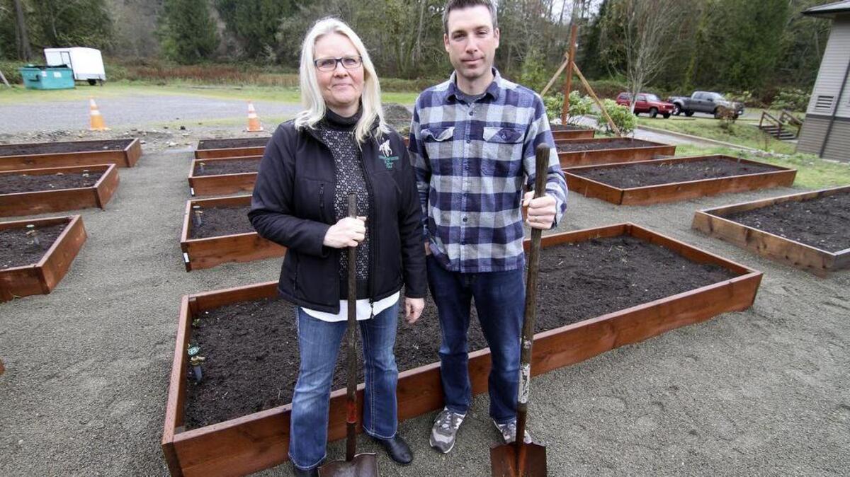 Harbor Covenant Church administrative assistant Christine Erikson and assistant pastor Blake Merwin pose with the recently-completed first stages of construction of the congregation’s new garden planter boxes.