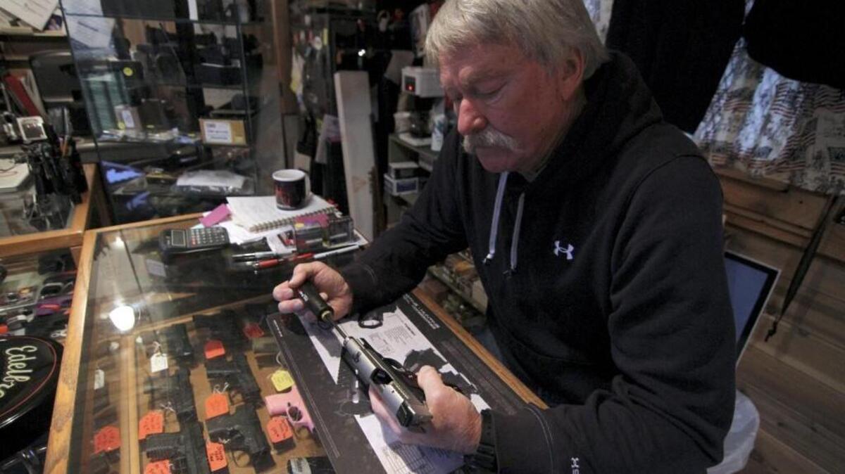 Bob McDaniel, owner of Gig Harbor Guns, cleans his personal carry weapon, a Sig Sauer brand .45 caliber handgun, in his Olalla shop Monday.