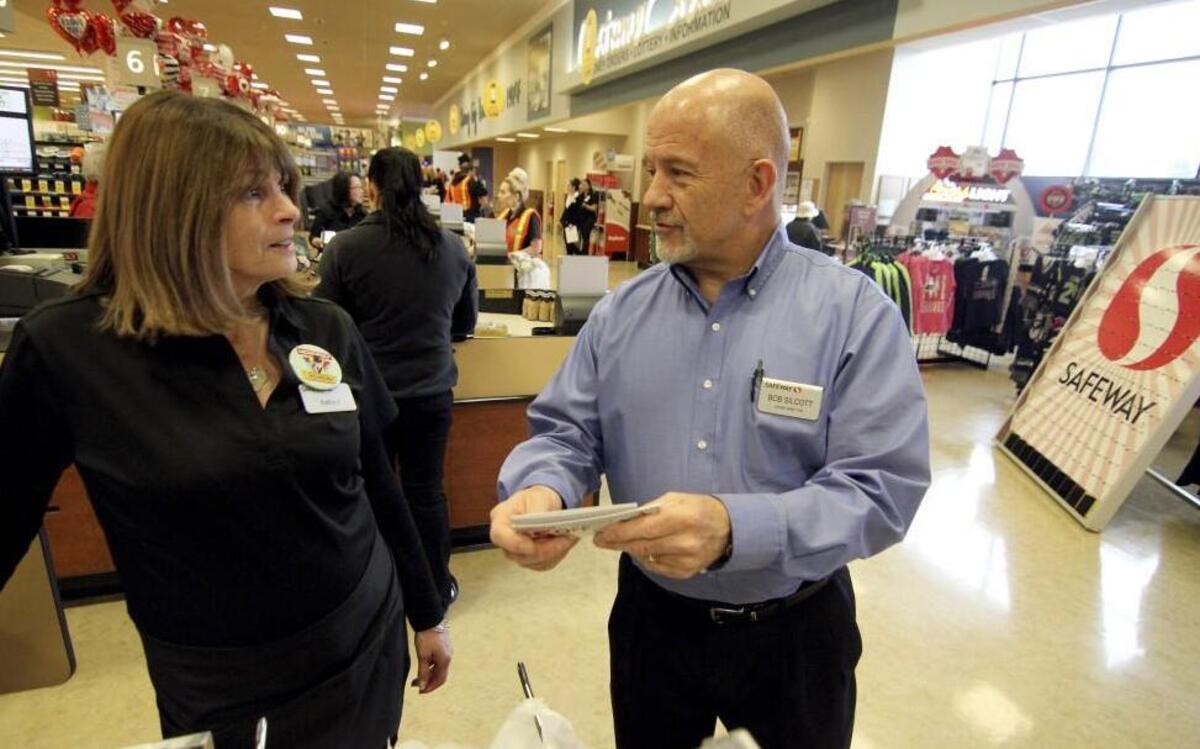 Safeway is welcoming some longtime employees back to work at the UpTown Gig Harbor store, including store manager Bob Silcott, right, and Kathy Jutte, the longest Gig Harbor employee, at 45 years of service. Seventy-two employees in all returned to the store. Jute and Silcott talk at one of the store’s check stands on Thursday.