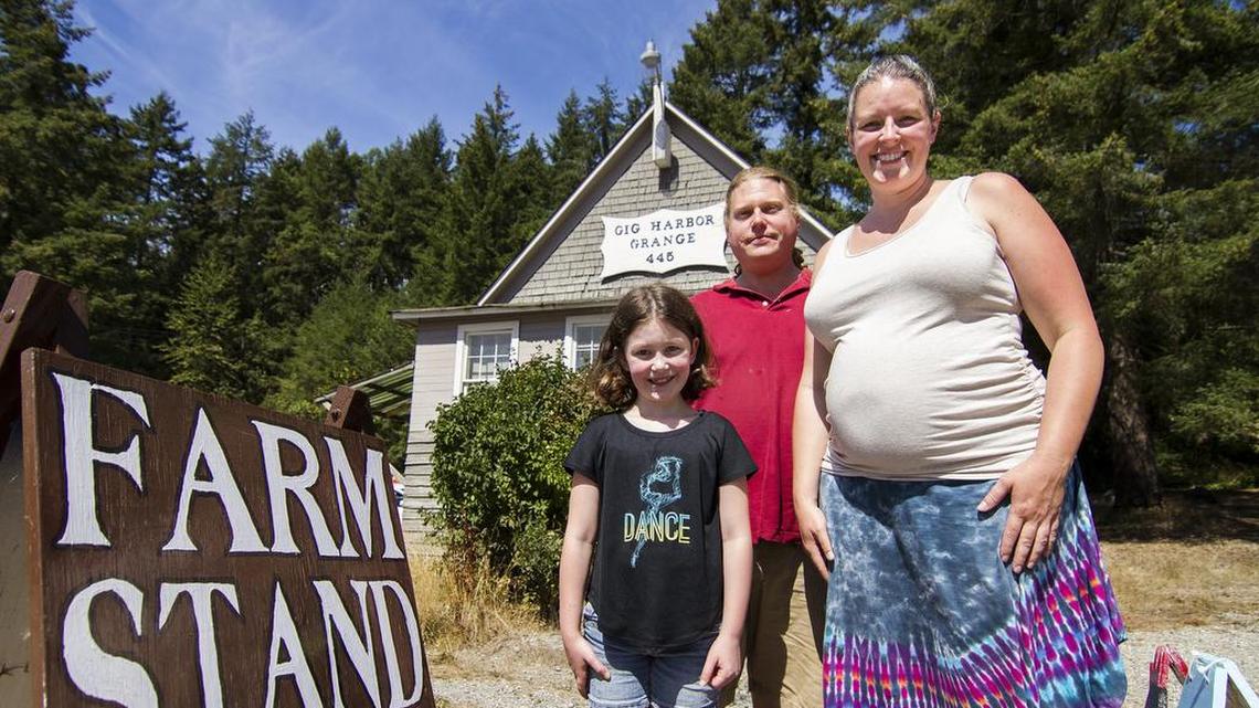 Scott and Jess Hogan, owners of Artondale Farm, stand for a portrait with their daughter, Loren, outside of the Gig Harbor Grange building on Friday. The Hogans recently purchased the building and plan on renovating it and using it for farm-related activities.