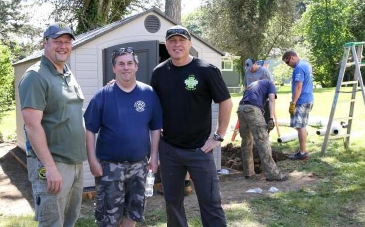 Contractor Chuck Lawson, left, volunteered his services Monday afternoon along with a large group of others to help build Gig Harbor resident Audie Graham, center, a new apartment. Gig Harbor Fire & Medic One Battalion Chief Lance O’Leary, right, a longtime friend of Graham’s, helped coordinate the work party.