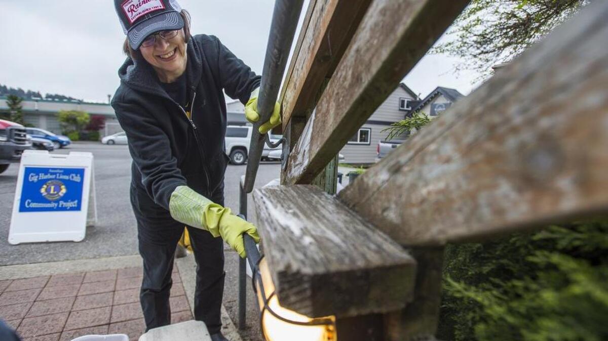 Lions Club member Ruth Peterson cleans one of the lights on the Finholm stairs in Gig Harbor on Saturday. The Lions Club will host another work party to clean the stairs on April 29, ahead of a rededication ceremony on May 6.