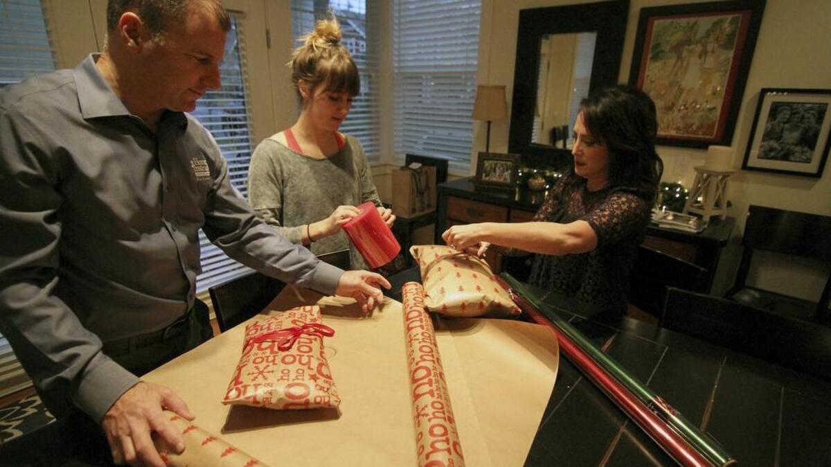 Todd, left, daughter Annie, and wife Lizzie O’Neill wrap presents on Monday morning for the Be a Santa to a Senior program hosted by Home Instead Senior Care. The program connects community members with local seniors who otherwise would not receive a gift for Christmas.