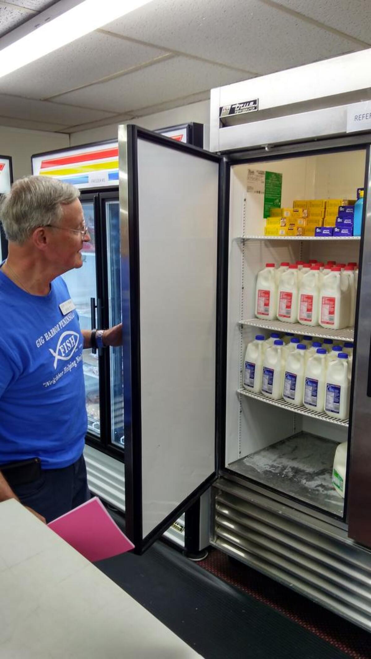 Ron Coen, president of the Gig Harbor Peninsula Fish food bank’s board, shows a refrigerator now full of food thanks to community donations.
