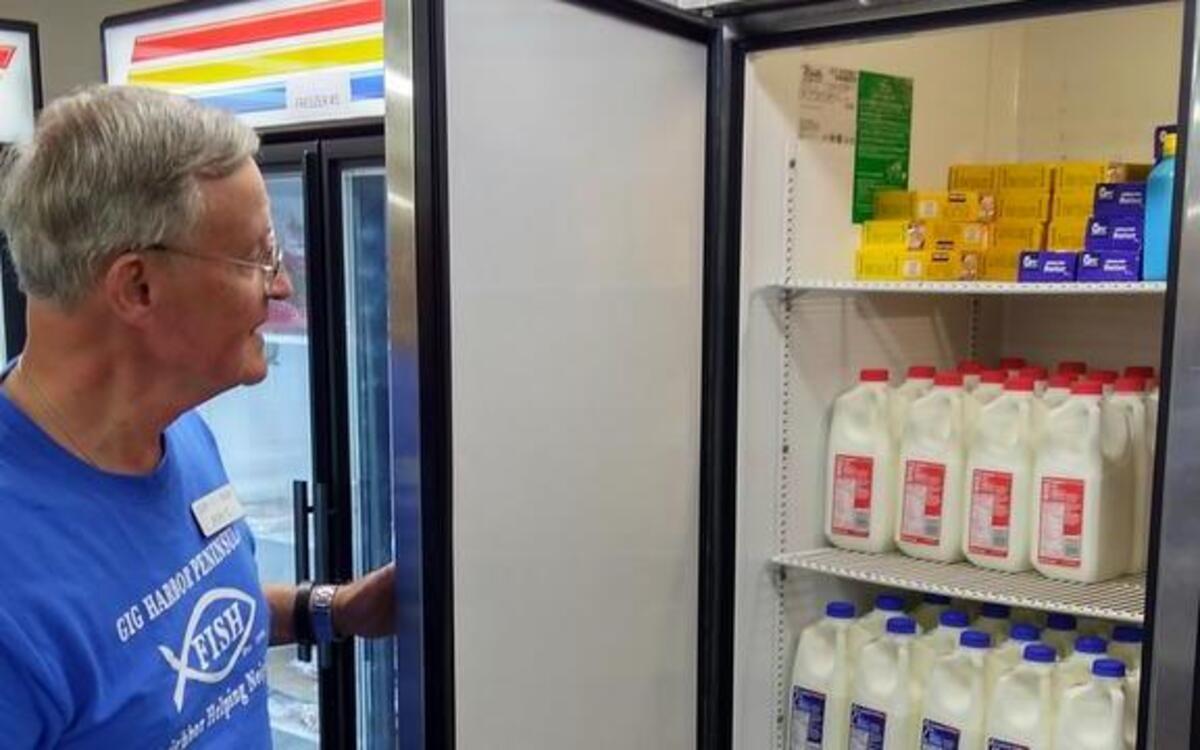 Ron Coen, president of the Gig Harbor Peninsula Fish food bank’s board, shows a refrigerator now full of food thanks to community donations.