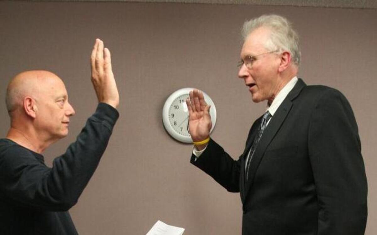 
Peninsula School District Superintendent Chuck Cuzzetto administers the oath to interim board member Jerry Gibbs during a meeting Thursday night at the district’s headquarters. Although Gibbs will only serve until November — about six meetings — he’ll be involved in the budget process as well as the lead up to a crucial maintenance and operations levy.
