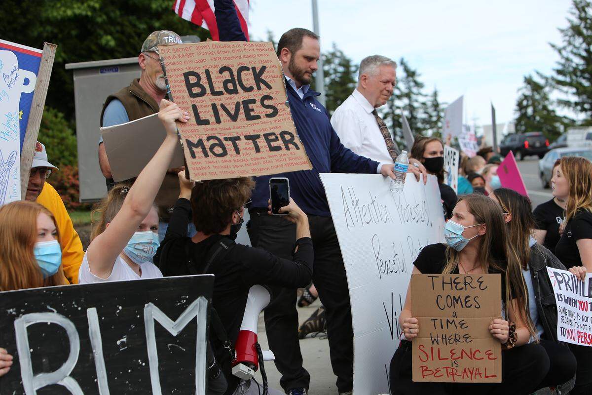 John Skansi (left) crouches down behind a group of young people at a Gig Harbor protest for Black Lives Matter last year. Photo by Ronnie Glover.