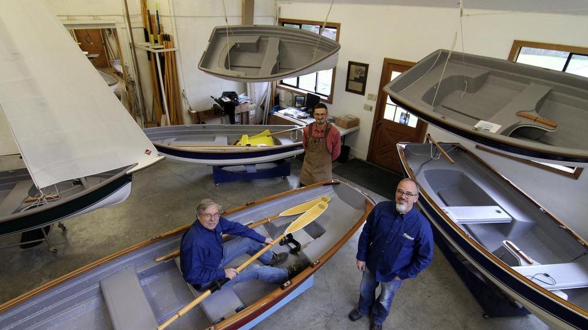 Gig Harbor Boat Works founder Dave Robertson, seated in boat, boat builder Falk Bock, center, and business manager John Paulson, right, pose proudly with their creations.