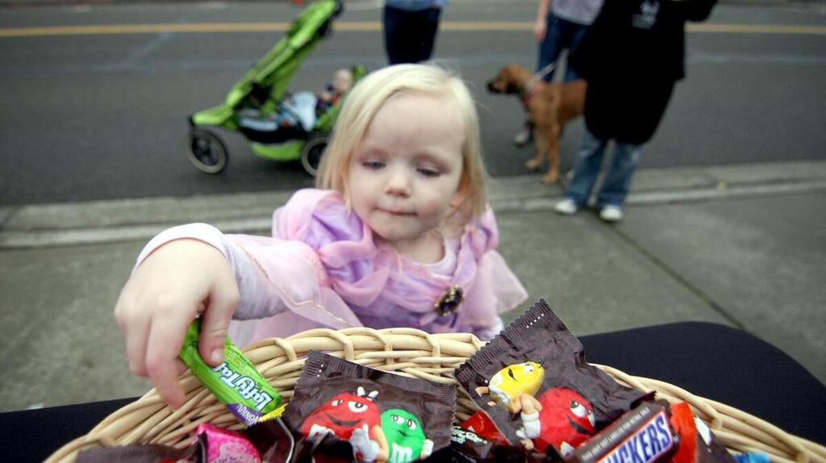 Shiloh Rushton reaches into a bowl full of candy as she and hundreds of other kids enjoyed fair skies and safety during the 2013 Gig Harbor trick-or-treat event along Harborview Drive.