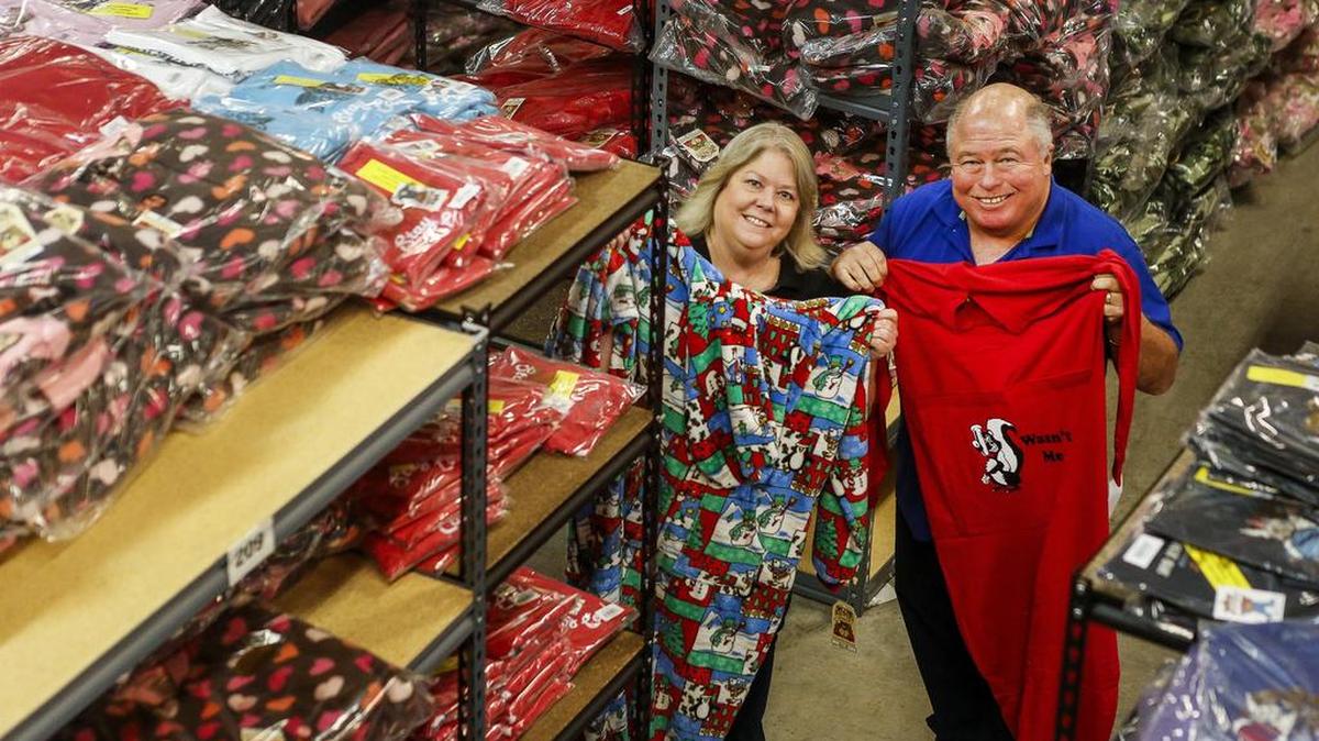 Tammy and John Fitzpatrick of Big Feet Pajamas hold up pajamas in their warehouse in Gig Harbor on Friday. Big Feet Pajamas makes pajamas for people of all ages. The couple started making footie pajamas for adults before expanding.