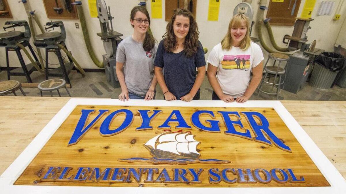 Grace Rosing, Laura Nelson and Katie Mandarino, from left, are three students who worked on a new sign for Voyager Elementary School. The sign is carved from four planks of cedar.