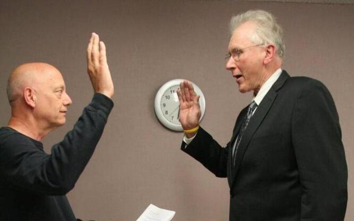 Peninsula School District Superintendent Chuck Cuzzetto administers the oath to interim board member Jerry Gibbs during a July 23 meeting at the district’s headquarters.