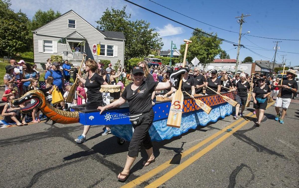 The Gig Harbor Dragons march alongside a replica dragon boat float during the Yo' Ho' Harbor Grande Parade in June 2016.