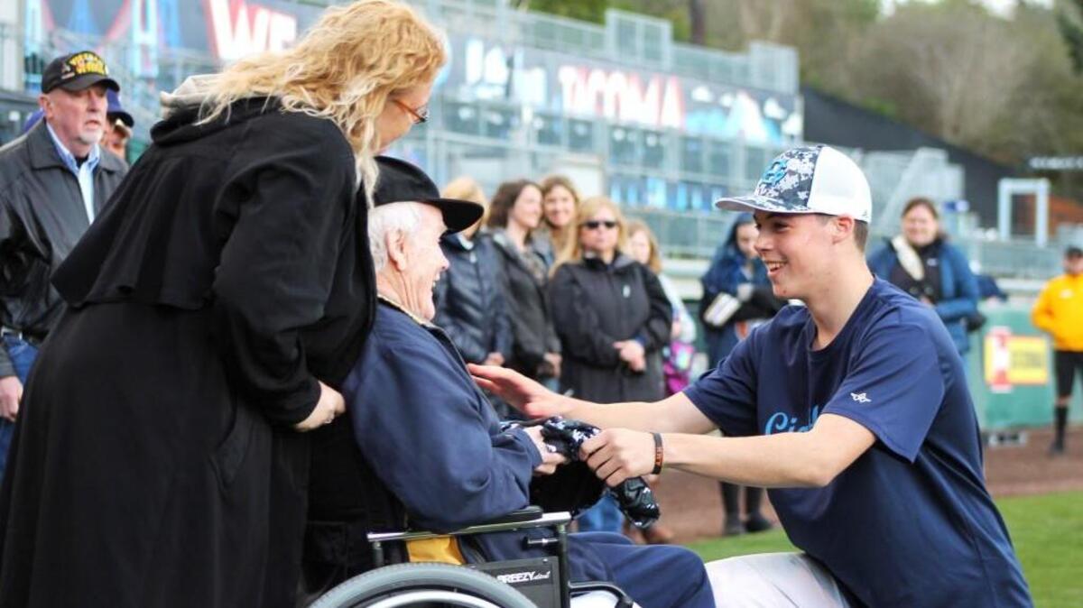 Gig Harbor High senior Logan Gerling, who was named the game’s most valuable player, hands his jersey to his grandfather, 1st Lt. Richard Goins, who served in the Korean War as a special-ops fighter pilot with the United States Air Force. Gig Harbor played South Kitsap in the second annual Tribute to our Troops baseball game at Cheney Stadium on Saturday.