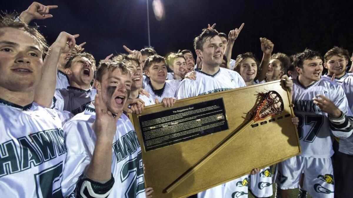 Peninsula celebrates while holding the Baggataway Bowl “Fire Stick” trophy after defeating Gig Harbor, 17-9.