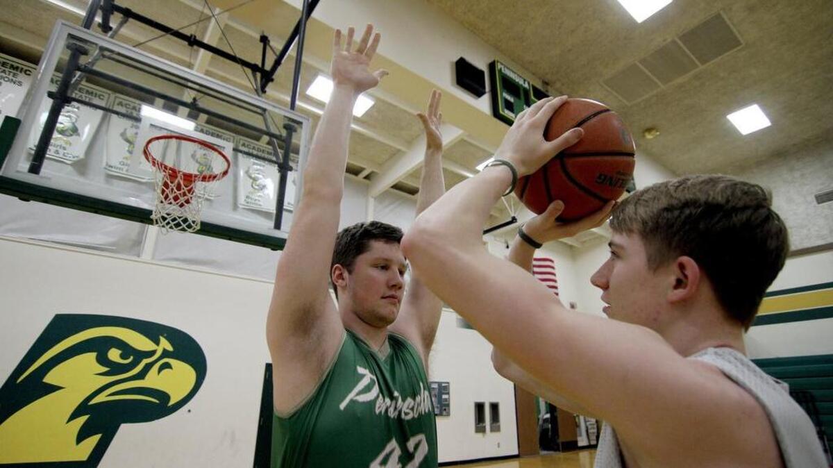Peninsula High players Jimmy Ritchie and Cade McGill practice last week at the school’s gym. Ritchie, at 6-foot-9, towers over the 6-foot-3 McGill.