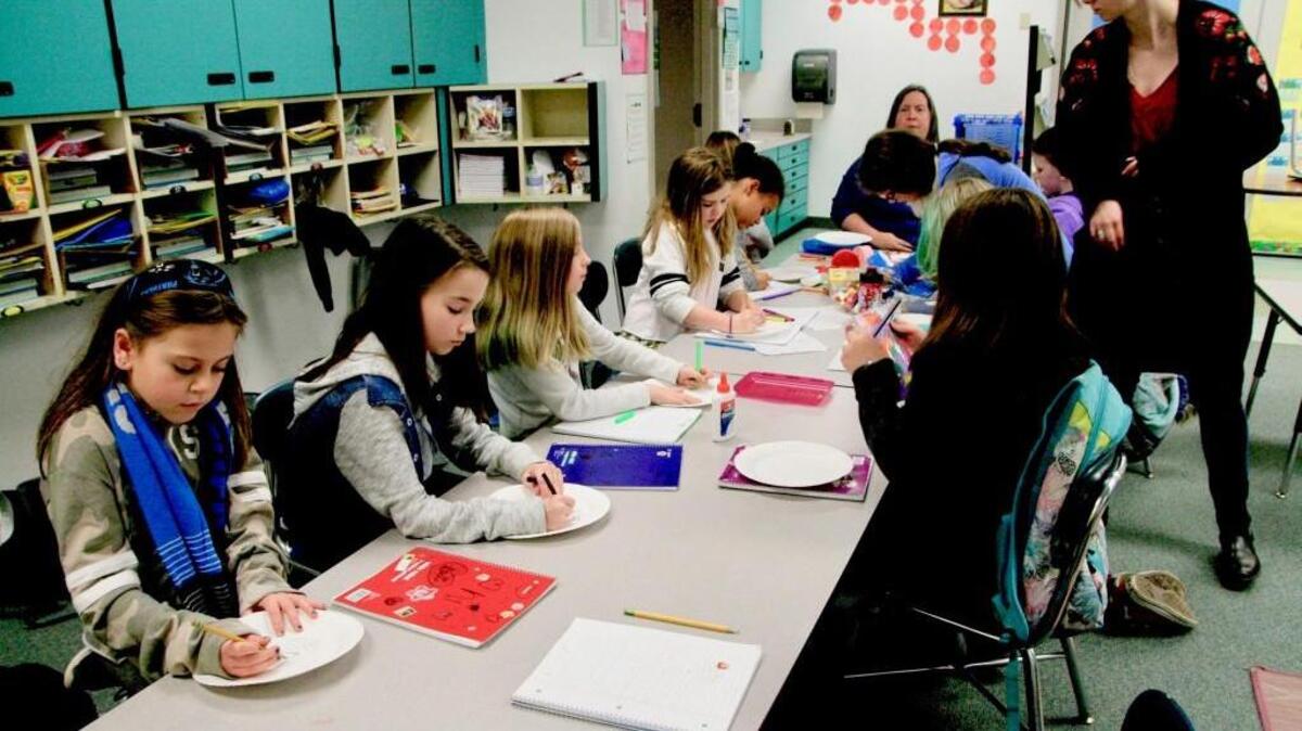 From left, Evergreen elementary “Little Toasters,” third-grader Lexi Johnson and fourth-graders Grace Roberts, Amelia Staples and Keyanna Davis working on an art project under guidance of Lori Mertens of Children’s Home Society, seated far end, and intern Chelsie Compton, standing.
