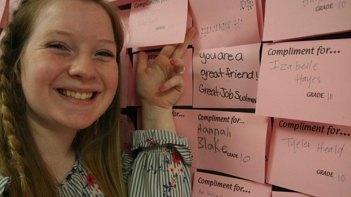 PHS sophomore Maddy Terry uncovers the content of one of the hundreds of “Share the Love” month notes covering the school’s commons wall.