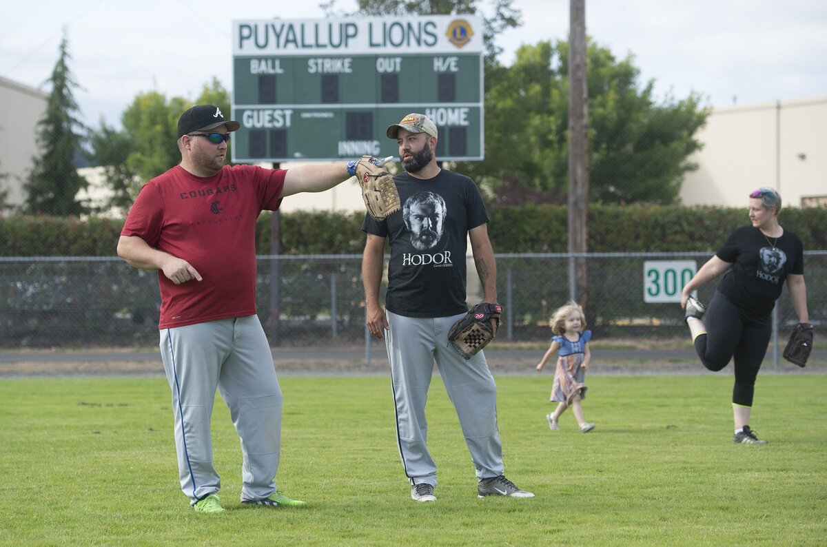 Paul Ankenman (left) of Federal Way talks with Captain Jack’s Hodors teammate Frankie Van Gelder of Puyallup as Gabrielle Ankenman and her daughter, Gwendolyn, 3, warm up before their opening night summer league softball game at Puyallup Recreation Center on Valley Avenue on Thursday, July 19.