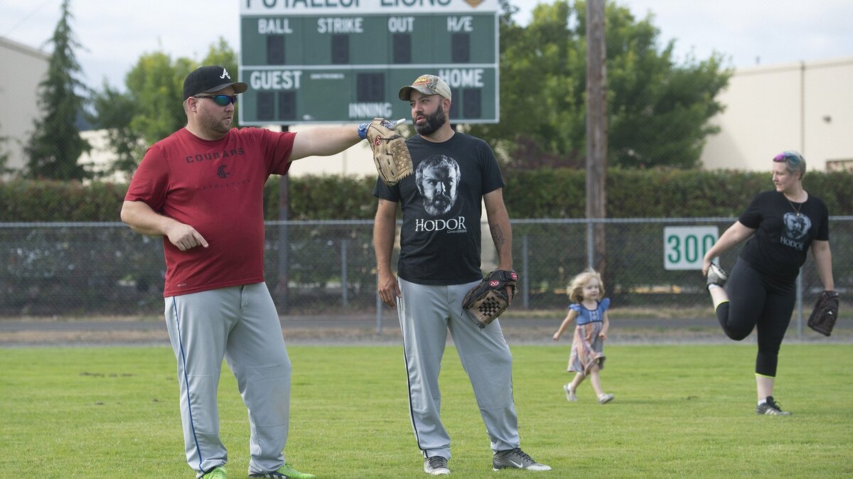 Paul Ankenman (left) of Federal Way talks with Captain Jack’s Hodors teammate Frankie Van Gelder of Puyallup as Gabrielle Ankenman and her daughter, Gwendolyn, 3, warm up before their opening night summer league softball game at Puyallup Recreation Center on Valley Avenue on Thursday, July 19.