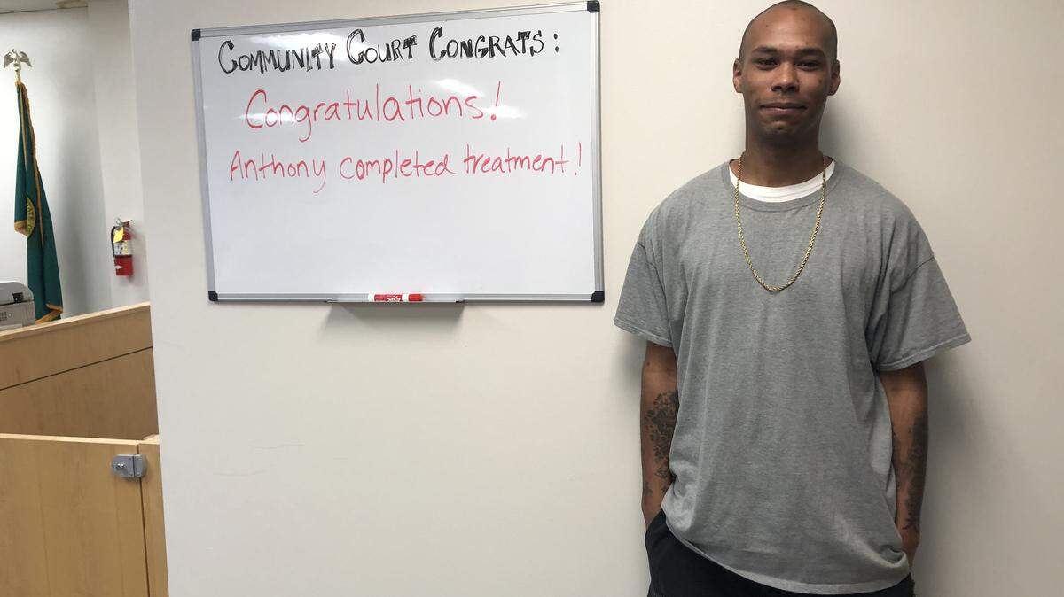 Community Court participant Anthony Johnson stands beside a sign celebrating his completion of the treatment part of the program. He's expected to graduate from Community Court in 2020.