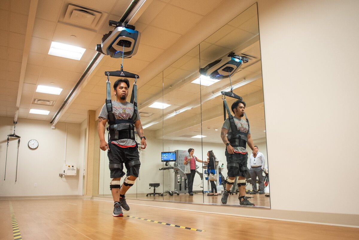 Mike Sebastian, a patient at MultiCare Good Samaritan Hospital, walks along a line with the help of a ZeroG Gait & Balance harness. ZeroG is a computer-controlled harness that hangs from the ceiling to help steady patients as they undergo physical therapy.